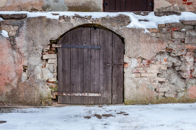 Close-up van oude houten deur in de winter. Oude boogdeur in de muur van het steenkasteel.