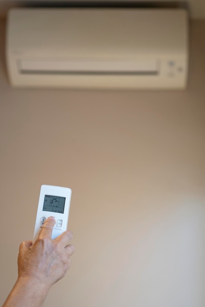 Close-up van oude vrouw handbediening airconditioner met afstandsbediening kopie ruimte