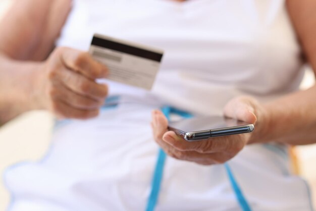 Close-up van oude vrouw met mobiele telefoon en bankkaart in handen oudere vrouw die epayments doet