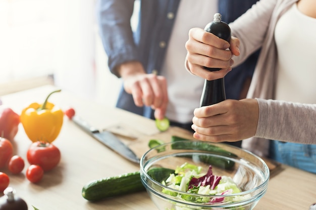 Close-up van paar dat gezond voedsel samen kookt in hun zolderkeuken thuis. Groentesalade bereiden, bijsnijden