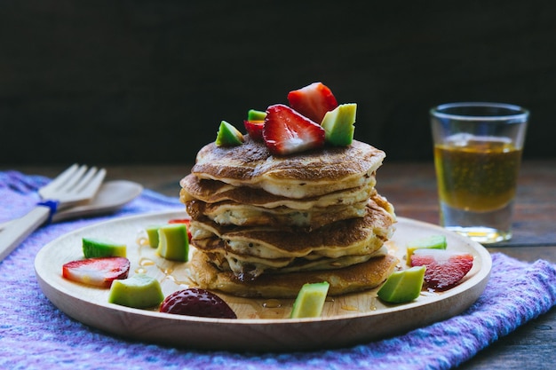 Close-up van pannenkoeken met fruit geserveerd op een bord op tafel tegen een zwarte achtergrond