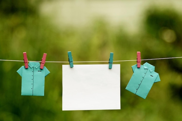 Foto close-up van papieren shirts die aan de waslijn hangen