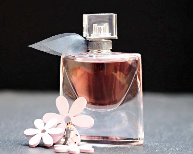 Foto close-up van parfumfles en wijnglas op tafel tegen een zwarte achtergrond