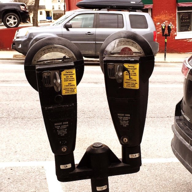 Foto close-up van parkeermeters met geparkeerde auto