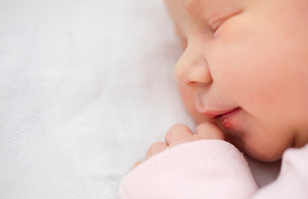 Close-up van pasgeboren babymeisje. Mooi één dag oud meisje dat in haar slaap glimlacht.