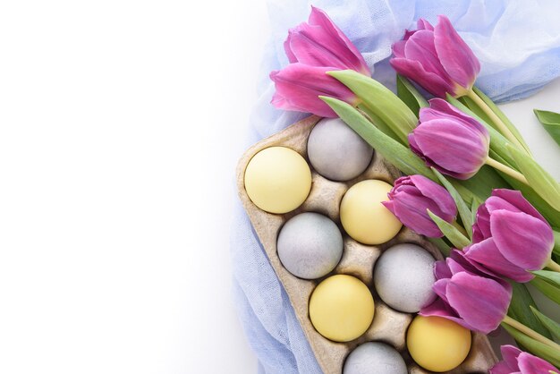 Close-up van pastel blauwe en gele paaseieren met violette tulpen met blauw doek servet op witte achtergrond met kopie ruimte