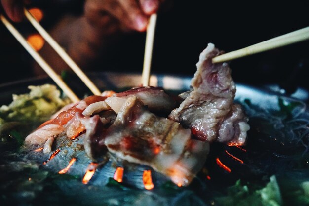 Foto close-up van persoon die eten bereidt op barbecue grill