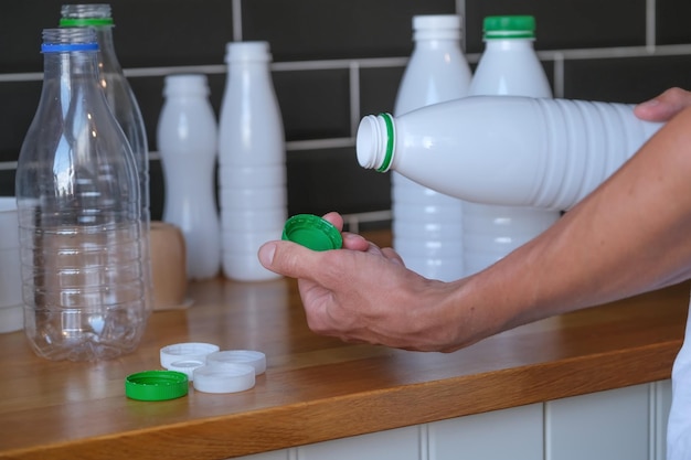 close-up van persoon die plastic deksel van fles melk scheidt terwijl plastic afval van voedsel wordt gesorteerd