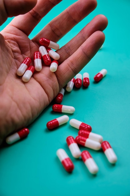 Foto close-up van pillen in de hand van een man tegen een groene achtergrond