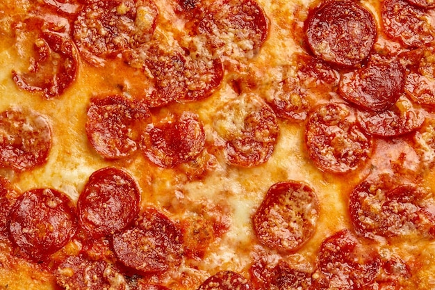 Close-up van plakjes pepperoni bedekt met gesmolten mozzarella op gebakken pizza