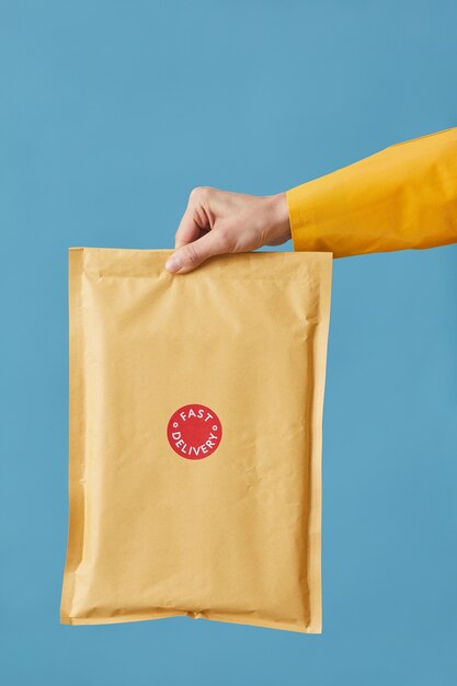 Close-up van postbode bedrijf pakket verpakt in papier geïsoleerd op blauw