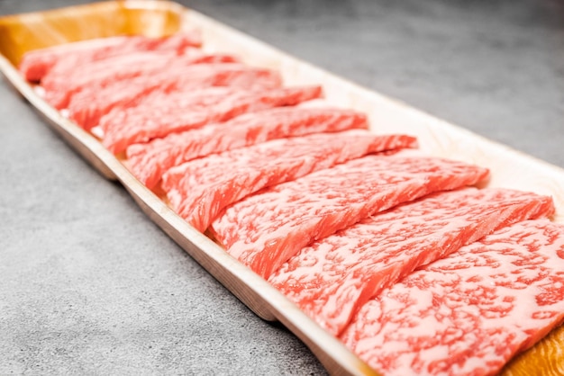 Close-up van premium zeldzame plakjes entrecote Wagyu A5-rundvlees met een hoogmarmeren textuur op dienblad geserveerd voor Yakiniku Sukiyaki en Shabu Place op achtergrond met kopieerruimte