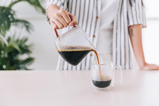 Close-up van professionele barista-hand die vers gezette koffie in een glazen mok giet. Koffie alternatieve methode bereiden