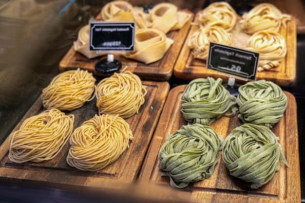Close-up van rauwe verse zelfgemaakte groene pasta tagliatelle. verse Italiaanse traditionele rauwe pasta op het aanrecht in de storewith blurr prijskaartjes