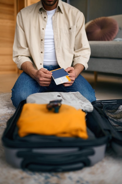 Foto close-up van reiskaartje en instapkaart in mannelijke handen over ingepakte koffer. klaar voor vakantie