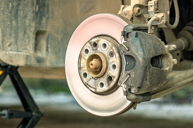 Foto close-up van remschijf van het voertuig met remklauw voor reparatie tijdens proces van nieuwe bandvervanging. autorem die in garage herstellen.