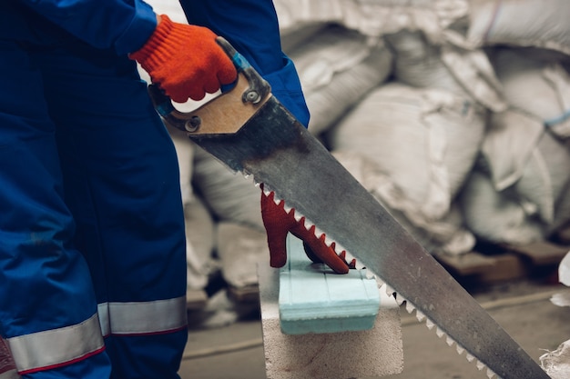 Close-up van reparateur in uniform, professionele bouwer die werkt met bouwmachines. proces van bouwen, renovatie van appartementen, repareren, bouwen. zagen, verbinden, snijden, voorbereiden.