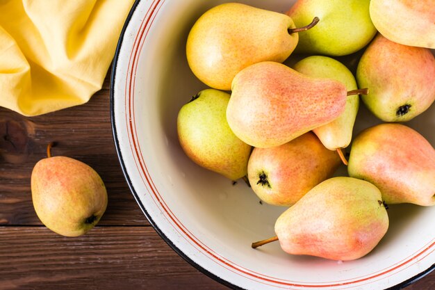 Close up van rijpe peren in een emaille plaat op een houten tafel. Bovenaanzicht