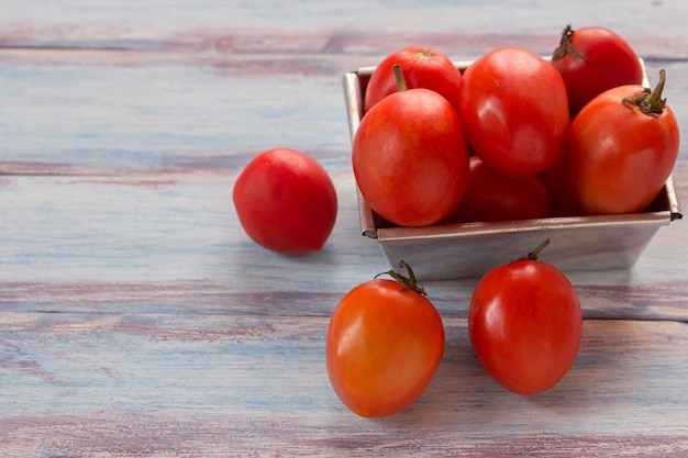 Close-up van rode cherry pruim tomaten in RVS kom op houten tafel achtergrond