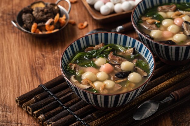 Close up van rode en witte tangyuan (tang yuan, kleverige rijst knoedel ballen) met hartige soep in een kom op houten tafel achtergrond voor winterzonnewende festival voedsel.