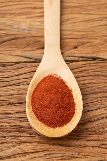 Close-up van rode paprika peper op een lepel over houten tafel.