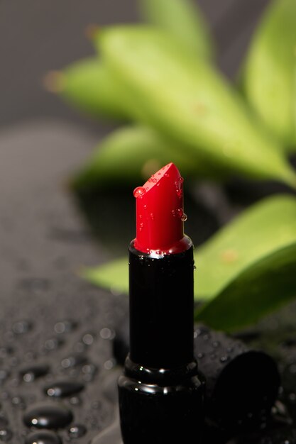 Close up van rode verzadigde lippenstift met waterdruppels.