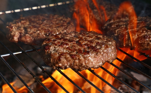 Foto close-up van rundvlees of varkensvlees vlees barbecue hamburgers voor hamburger bereid gegrild op bbq vuur vlam grill, hoge hoekmening