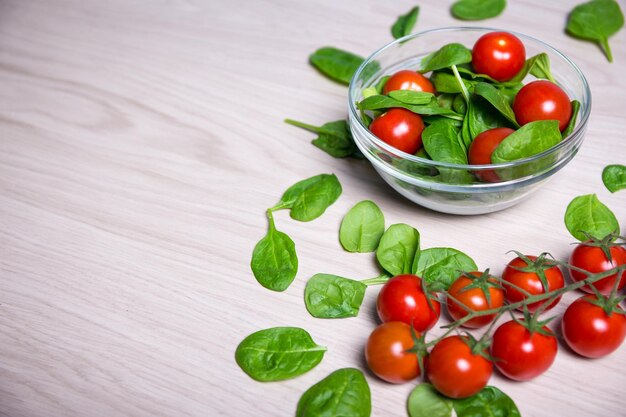 Close up van salade met spinazie en tomaten en kopieer ruimte op houten tafel