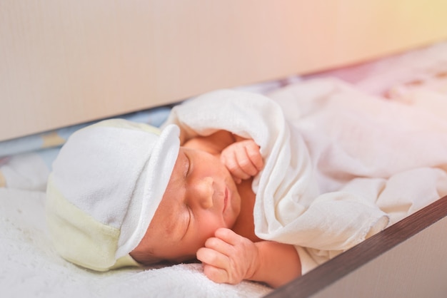 Close up van schattige pasgeboren baby dutje doen op witte kanten lakens.