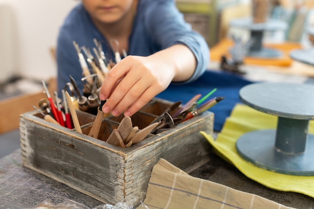 Close-up van schooljongen die klein Paletmes neemt voor het beeldhouwen van figuren