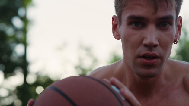 Close-up van serieuze sportman die basketbaloefening maakt met bal buiten