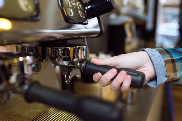 Close up van serveerster koffie maken met professionele machine in een coffeeshop.