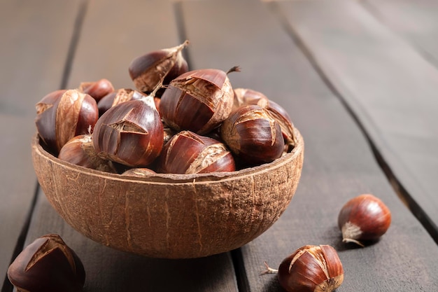 Close-up van smakelijke kastanjes in een kom op houten tafel