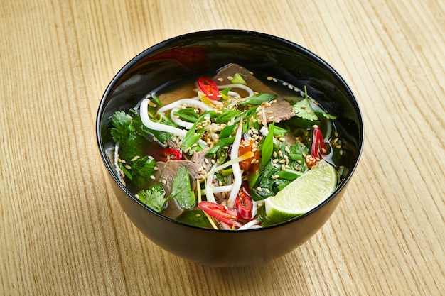 Close-up van smakelijke, traditionele pho Vietnamese soep bestaande uit bouillon, rijstnoedels, kruiden en vlees
