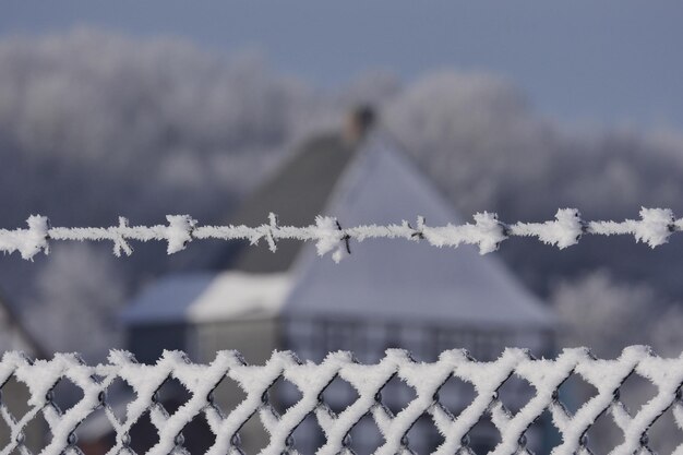 Foto close-up van sneeuwbedekt hek en prikkeldraad tegen het huis