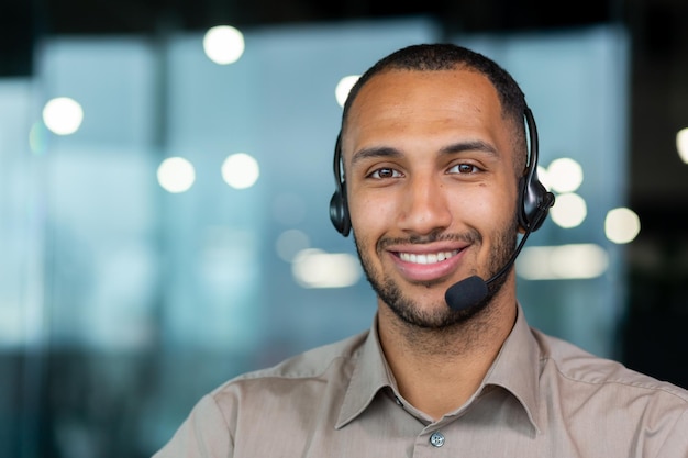 Close-up van Spaanse mannelijke werknemer met videoheadset glimlachend en kijkend naar camera technische ondersteuningsmedewerker