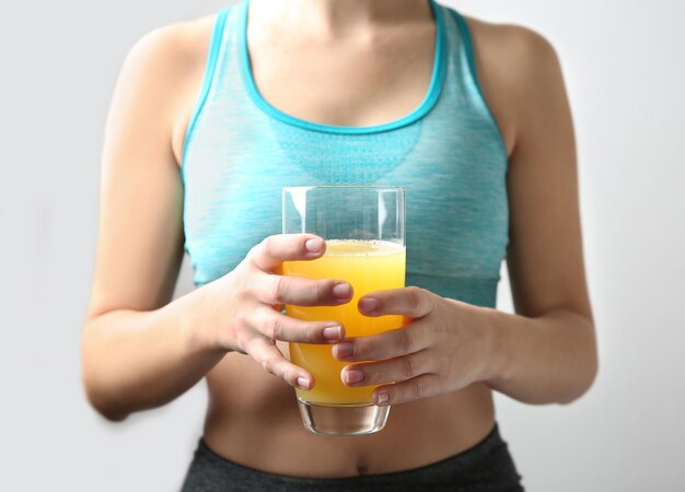 Close-up van sportieve vrouw met glas jus d'orange