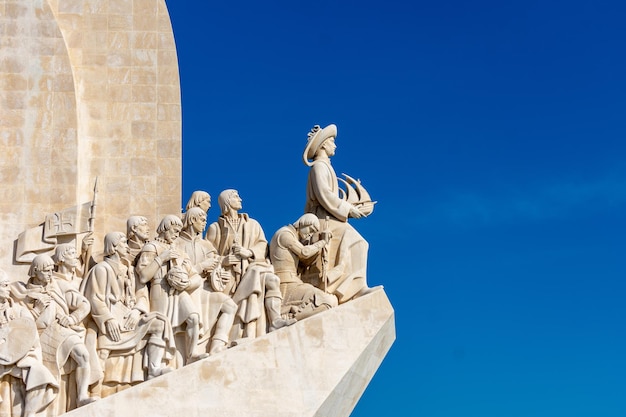 Close-up van standbeelden op het monument aan de ontdekkingen op de blauwe hemel van Lissabon