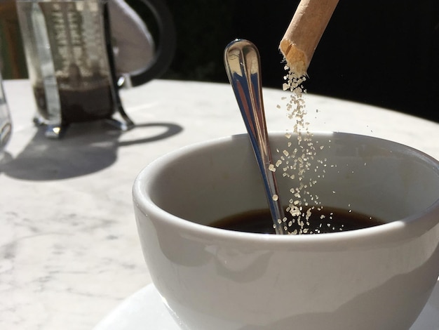 Close-up van suiker die in een koffiekop wordt gegoten