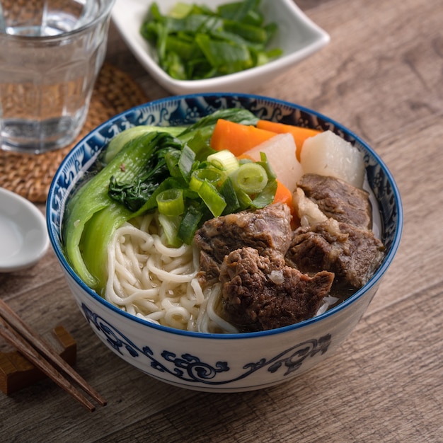 Close-up van Taiwanese beroemde gerechten met gesneden gestoofde rundvlees schenkel en groenten in een kom op houten tafel