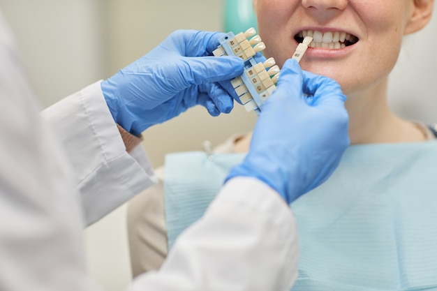 Close-up van tandarts in beschermende handschoenen die tandimplantaten voor patiënt bij kliniek kiezen