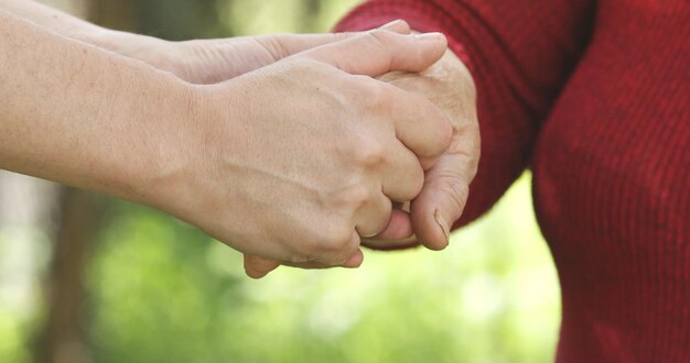 Close-up van teder gebaar tussen twee generaties. Jonge man hand in hand met een senior dame.