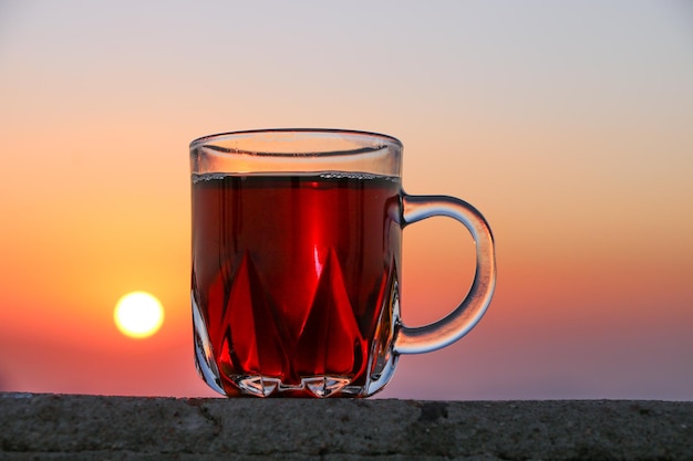 Close-up van thee in een kopje tegen een oranje hemel