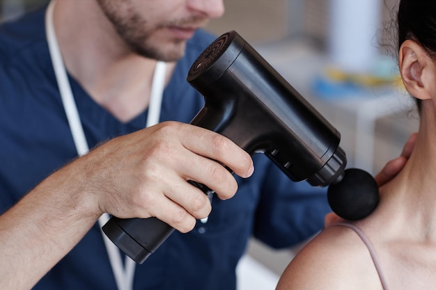 Close-up van therapeut die tijdens een medische ingreep met de masseur massage geeft aan de patiënt