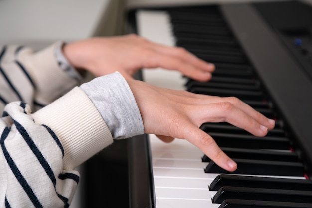 Close-up van tiener piano spelen in thuis muziekstudio.