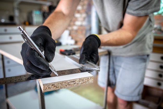 Close-up van timmerman die liniaal en potlood vasthoudt terwijl hij markeringen maakt op het hout aan de tafel in de werkplaats.