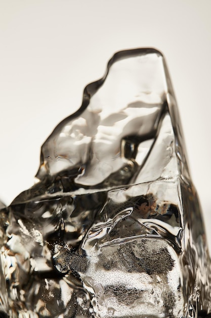 Close-up van transparant smeltend ijsblokje geïsoleerd op grijs
