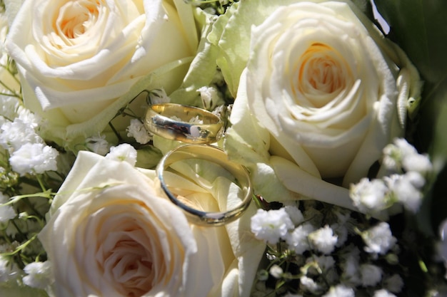Close-up van trouwringen op een bouquet witte rozen
