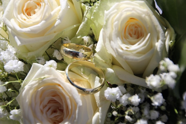 Foto close-up van trouwringen op een bouquet witte rozen