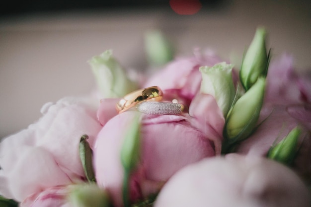Close-up van trouwringen op roze bloemen